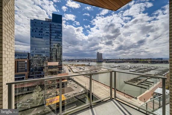View from a high building balcony overlooking a cityscape with a waterfront and marina.