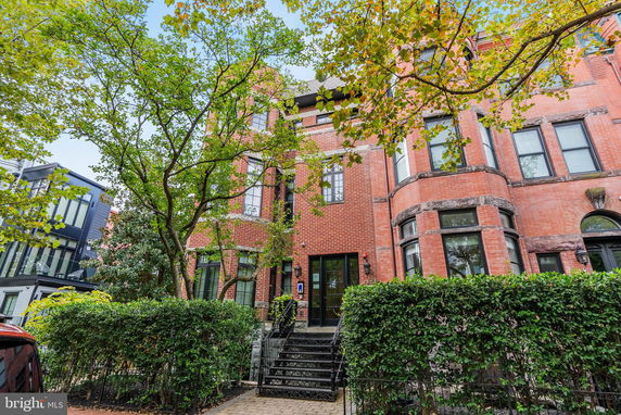 Front view of a multi-story brick building with large windows and an ornate entrance.