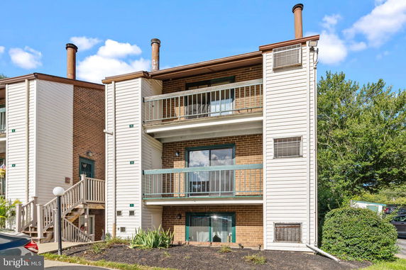 Front view of a three-story apartment building with balconies and a brick facade.