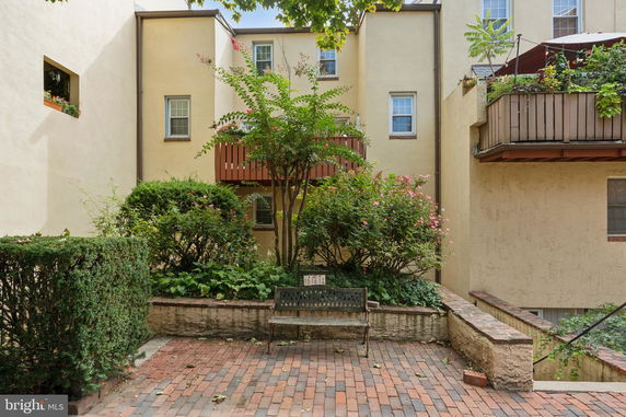 Front view of a multi-story building with balconies and surrounding greenery.