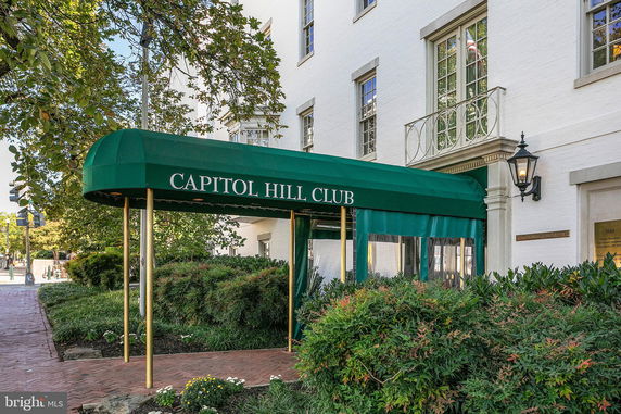 Entrance view of a building with a green canopy labeled Capitol Hill Club.
