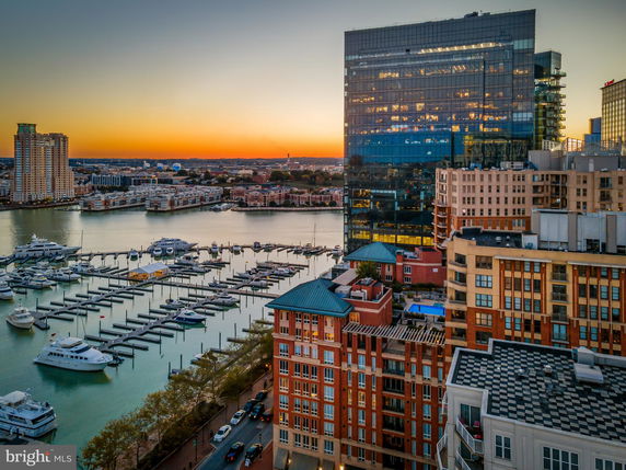 Panoramic view of waterfront buildings and marina with yachts at sunset.