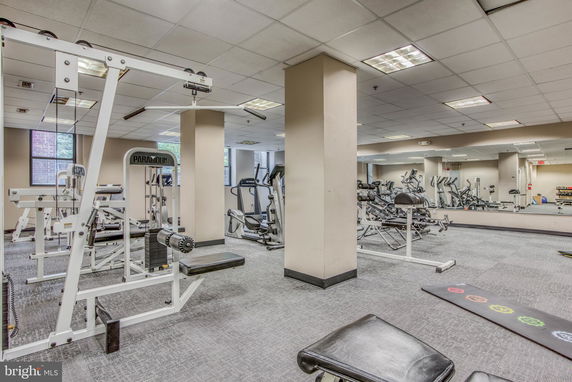 Indoor gym area with various exercise equipment and mirrored walls.