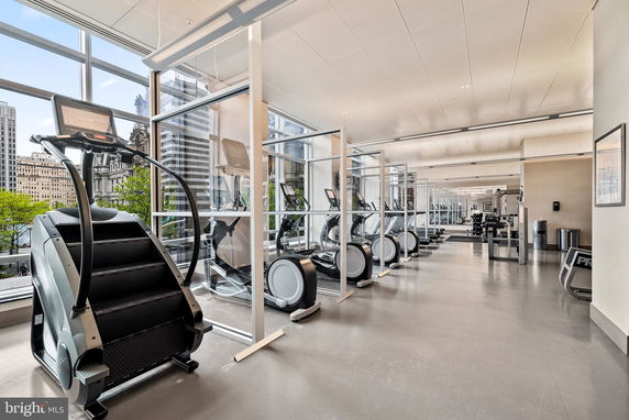 Interior view of a modern gym with exercise machines and large windows.
