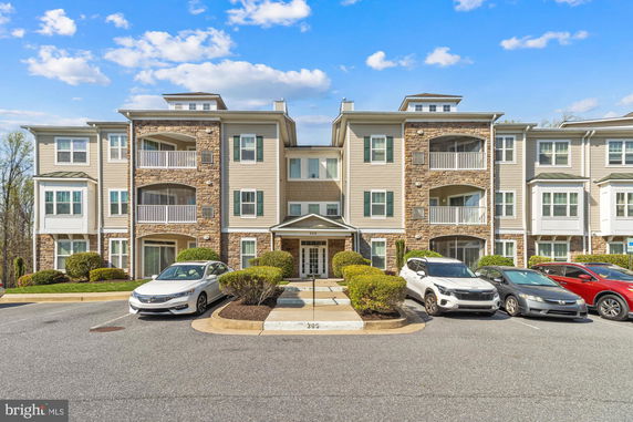 Front view of a three-story apartment building with balconies and stone accents.