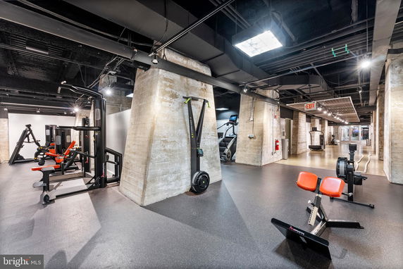 Interior view of a gym with exercise equipment and concrete pillars.