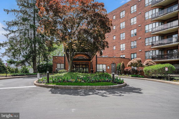 Front view of a multi-story brick building with balconies and entrance driveway.