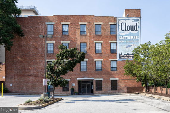 Front view of a four-story brick building with multiple windows and an entrance at street level.