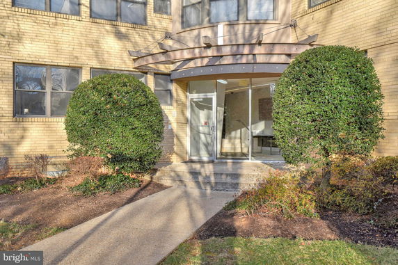 Front view of a building entrance with glass doors and brick facade.