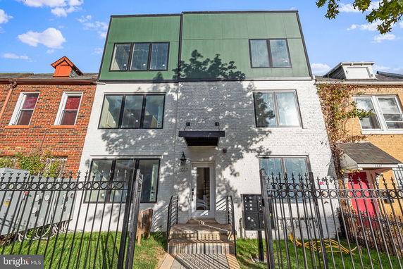 Front view of a three-story house with a modern facade and large windows.