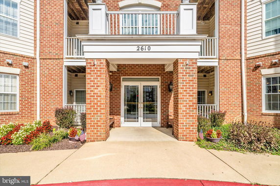 Front view of a brick building entrance with double glass doors.