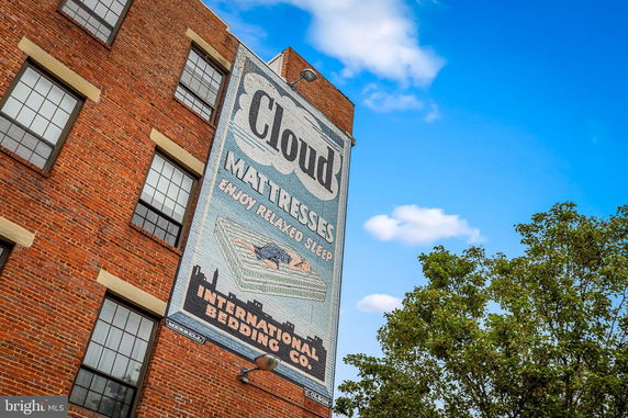 Front view of a brick building with large painted advertisement on the side.