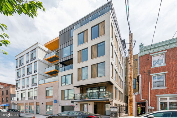 Front view of a multi-story modern apartment building with large windows and balconies.