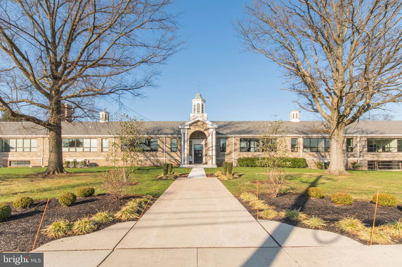 Front view of a large, single-story building with a central entrance and cupola.