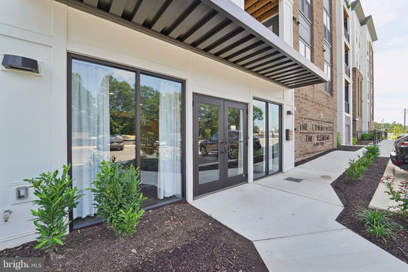 Front view of a modern multi-story building with glass doors and large windows.