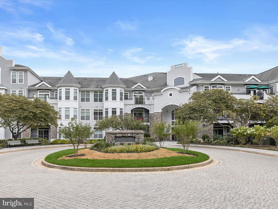Front view of a multi-story residential building with bay windows and shingled roof.