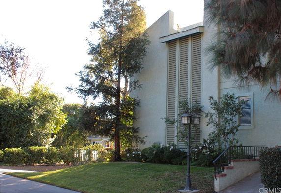 Side view of a multi-level house with large vertical windows and surrounding trees.