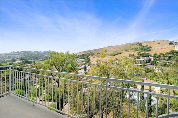 Wide-angle view from a balcony overlooking surrounding hills and buildings.