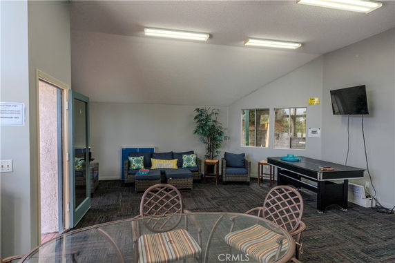 Interior view of a recreation area with seating, a table, and a TV on the wall.