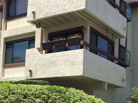 Exterior view of a building with a balcony featuring potted plants.