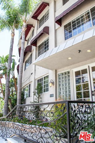 Front view of a multi-story building with multiple windows and a decorative railing.