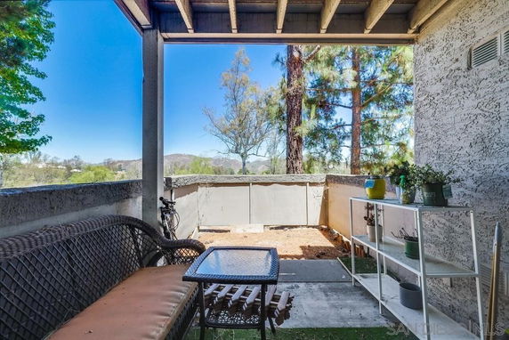 View from a covered patio area with a small fence, looking out towards trees and distant hills.