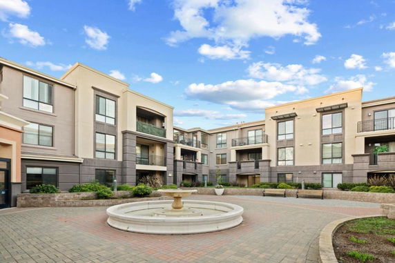 Front view of a modern multi-story apartment building with balconies and a courtyard.