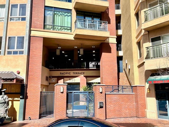 Front view of a multi-story building with balconies and a gated entrance.