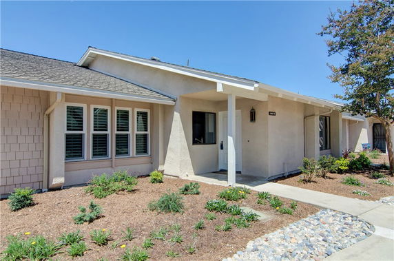 Front view of a single-story house with a covered entrance and landscaped garden.
