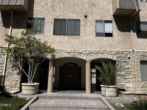Front view of a multi-story building with a textured exterior and stone accents.