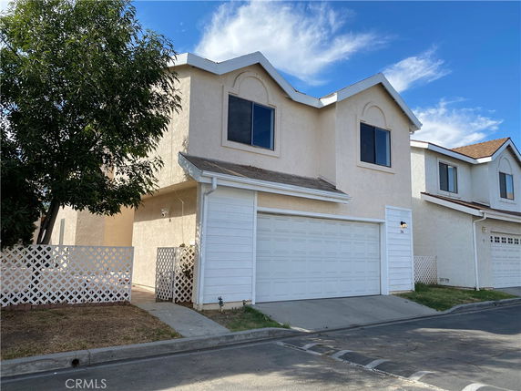 Front view of a two-story house with a white garage door and beige exterior.
