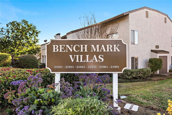 Front view of a multi-unit residential building with a sign reading 'Benchmark Villas'.