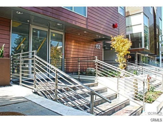 Front view of a modern multi-story building with metal railings and steps leading to the entrance.
