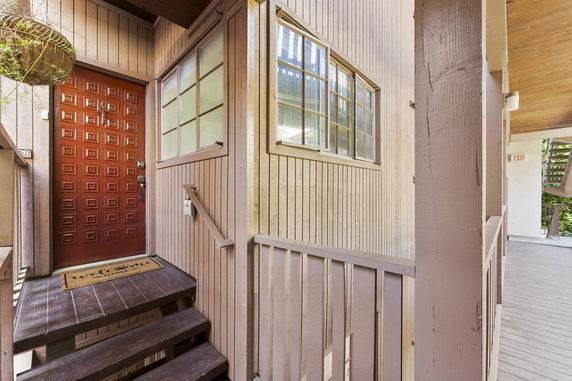 Front view of a house entrance with a red door and wooden siding.