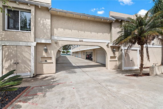 Front view of a two-story building with an archway entrance and garages.