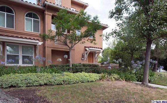Front view of a multi-story house with decorative plants and a pathway.