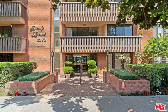 Front view of a multi-story building with balconies and a brick facade.