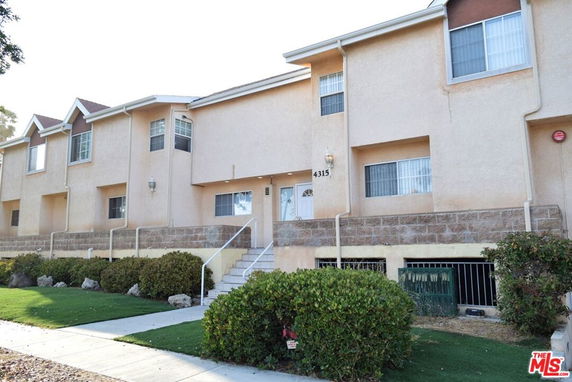 Front view of a multi-story residential building with stairs leading to the entrance.