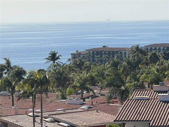 Panoramic view of a seaside area with tiled roofs and a large building near the ocean.