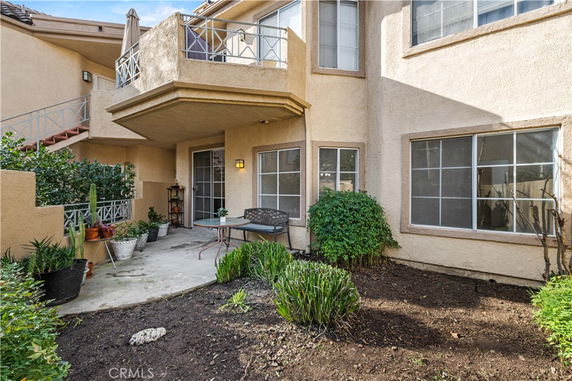Front view of a beige two-story house with balconies and a patio area.