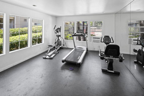 Indoor gym room with exercise equipment and mirrored wall.