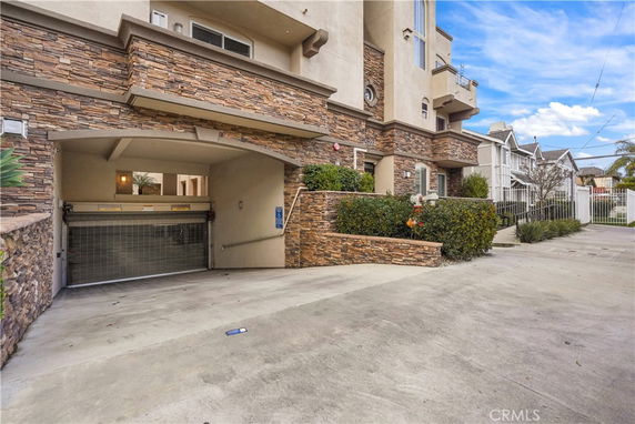 Front view of a house with stone accents and an entrance to a covered parking area.
