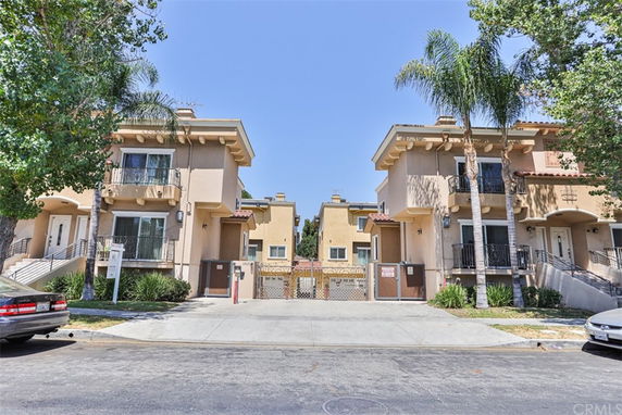 Front view of a two-story residential building with balconies and staircase entrance.