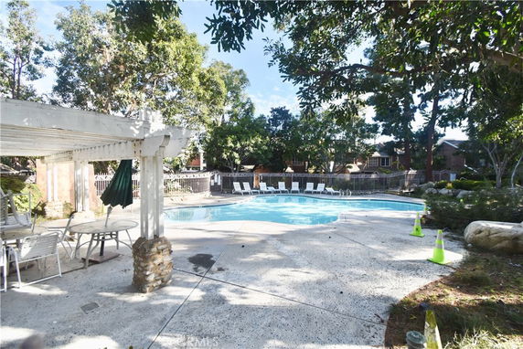 Outdoor swimming pool area with trees and seating.