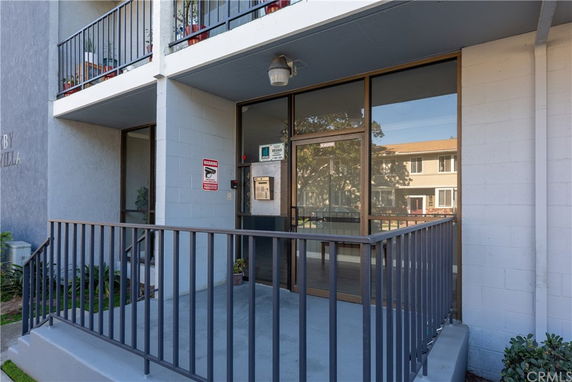 Front view of a building entrance with a glass door and a metal railing.