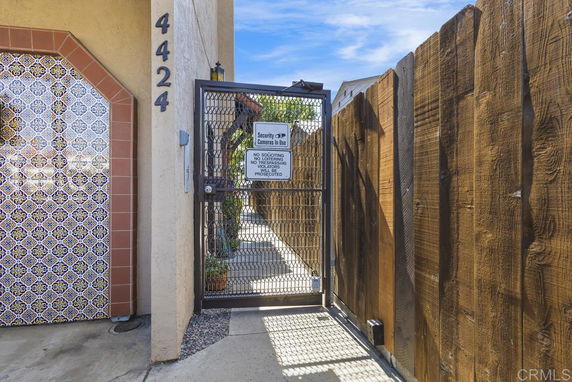 Front view of a gate entrance with decorative tiles on a wall.