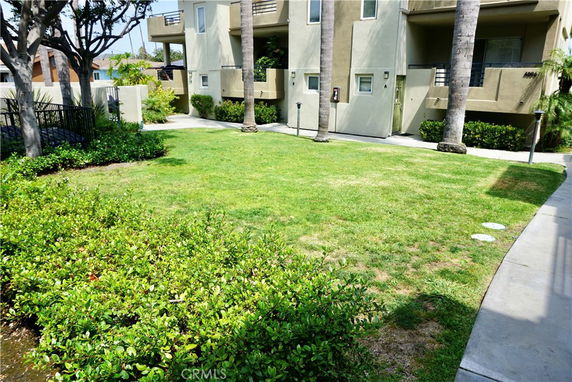 Front view of a multi-story building with balconies and surrounding greenery.