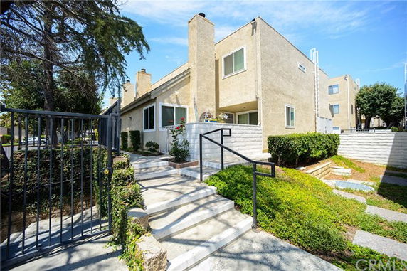 Front view of a two-story house with stairs leading to the entrance.