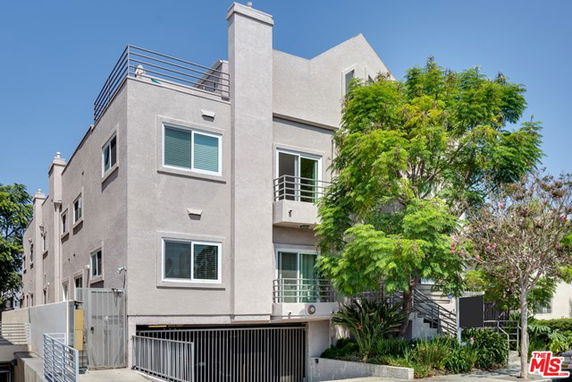 Front view of a multi-story residential building with balconies and a gated entrance.