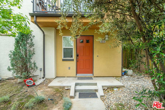 Front view of a house entrance with a red door and small steps leading up.